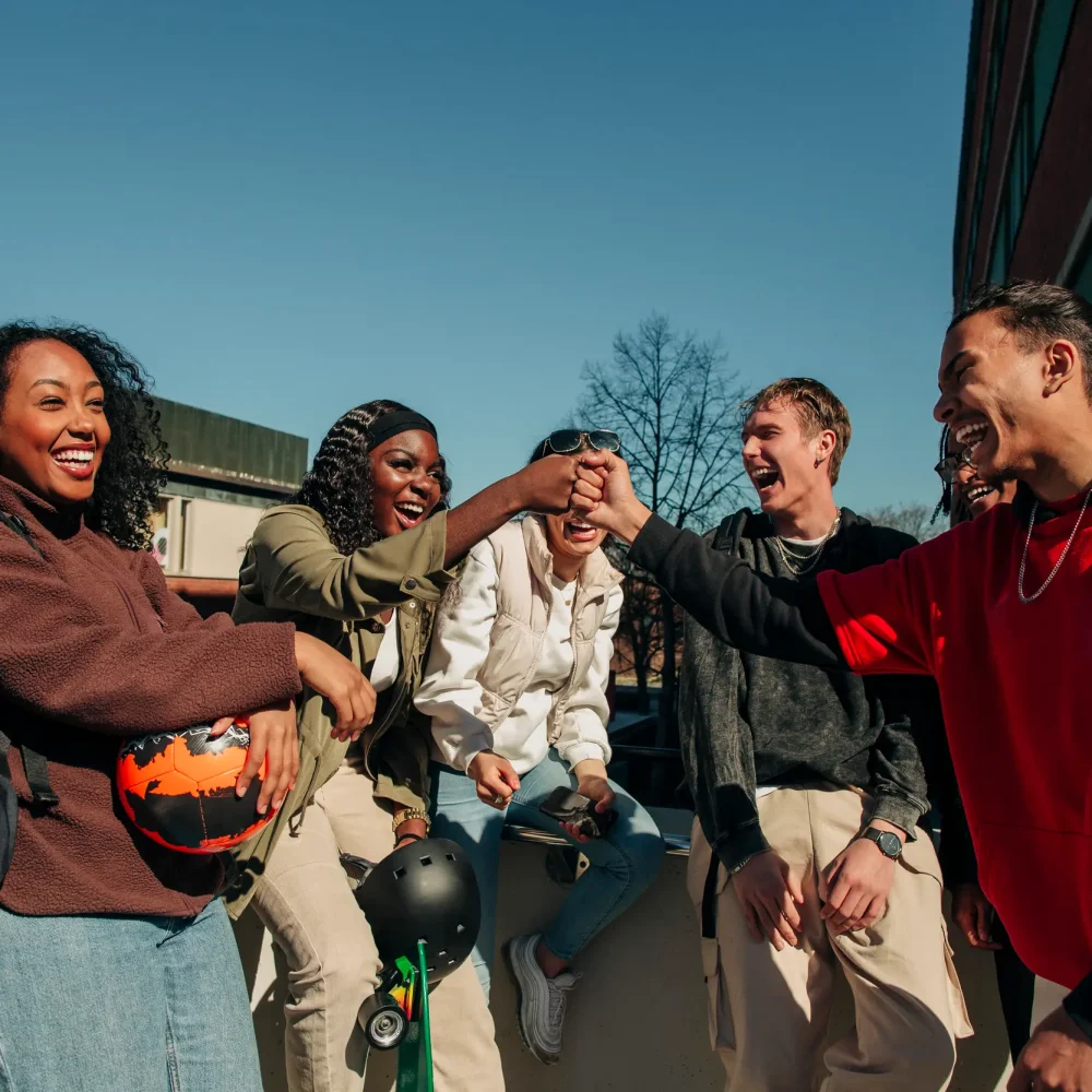 Glad tjej och kille gör fistbump stående bland vänner under en klassförsäljning