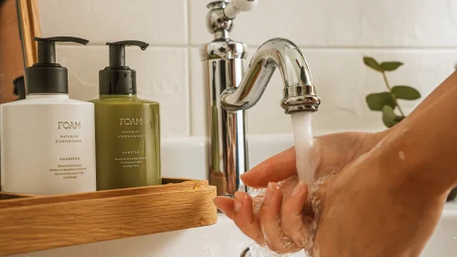 Handtvätt under kran med paket av handtvål och handkräm från foam