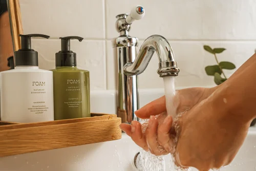 Handtvätt under kran med paket av handtvål och handkräm från foam