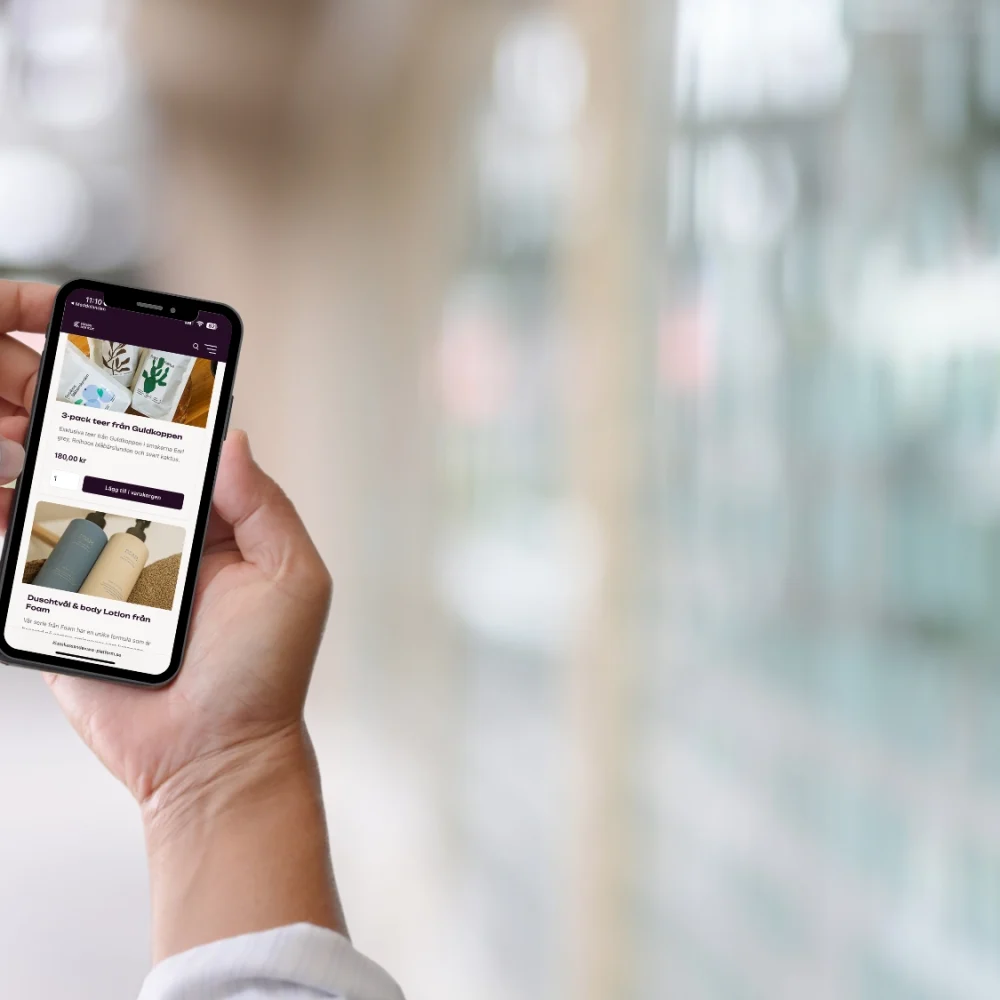 man som håller i mobil och scrollar igenom klasskontots webshop