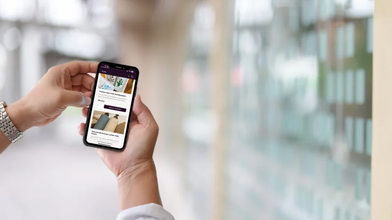 man som håller i mobil och scrollar igenom klasskontots webshop