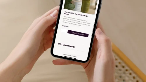 kvinna som håller mobil med klasskontot webshop på skärmen