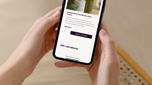 kvinna som håller mobil med klasskontot webshop på skärmen