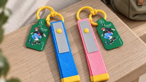 Reflexpaket Colorline med ett blått och ett rosa reflexband med gula detaljer på en träbänk.